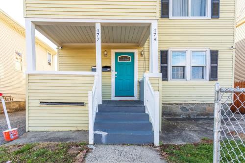 a yellow house with a blue door and stairs at The B&W Haven 5BR Home with yard theater in Bridgeport