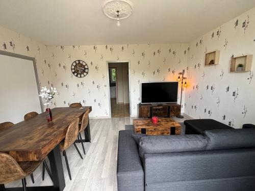 un salon avec un canapé, une table et une télévision dans l'établissement appartement type 5 proche circuit des 24h du mans, au Mans