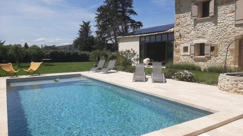 a swimming pool with chairs and a house at Mas le Jas in Cavaillon