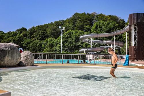 un jeune garçon debout dans l'eau dans une piscine dans l'établissement Gîte,bergerie en moyenne montagne, à Lacaze