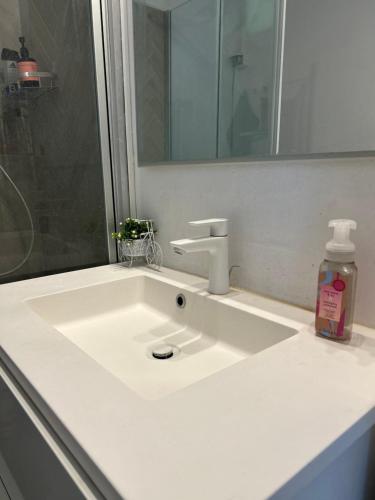 a white bathroom sink with a mirror and a bottle of soap at Cozy spot, Free Netflix and Prime in Vallensbæk
