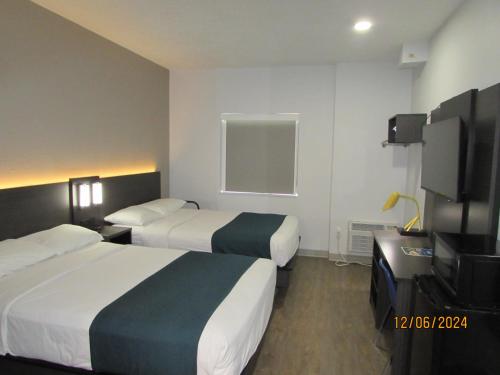 a hotel room with two beds and a flat screen tv at Motel 6-West Des Moines, IA in West Des Moines