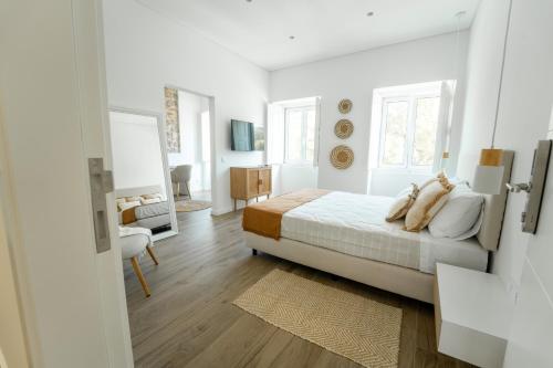 a white bedroom with a bed and a living room at Ria View Guesthouse in Faro