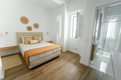 a bedroom with a bed with white walls and wooden floors at Ria View Guesthouse in Faro