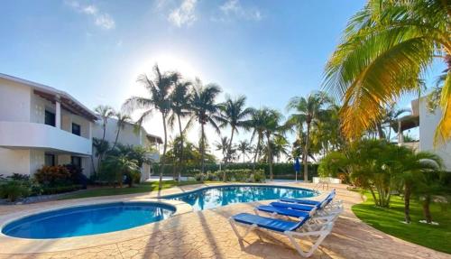 a resort swimming pool with lounge chairs and palm trees at Villa Ángeles - Elegancia en la Zona Hotelera in Cancún