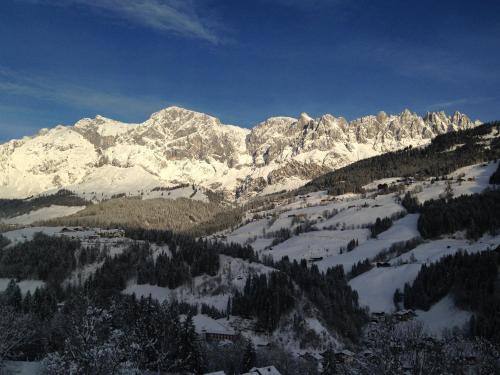 a snow covered mountain range with a town and trees at Alpendomizil Pia in Mühlbach am Hochkönig