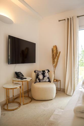 a living room with a chair and a tv on the wall at The White Knight Premium Boutique Hotel in Għajnsielem