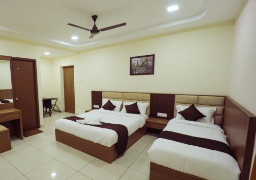 ein Schlafzimmer mit zwei Betten und einem Deckenventilator in der Unterkunft JKInn in Vellore