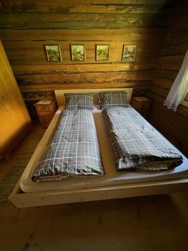 two beds in a room with wooden walls at Peintnerhof Almhütte in Innervillgraten