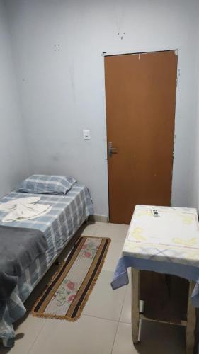 a bedroom with a bed and a table and a door at Pousada ji Paraná in Ji-Paraná