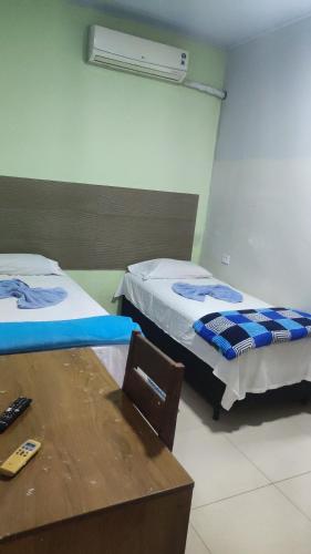 a room with two beds and a table and a desk at Pousada ji Paraná in Ji-Paraná