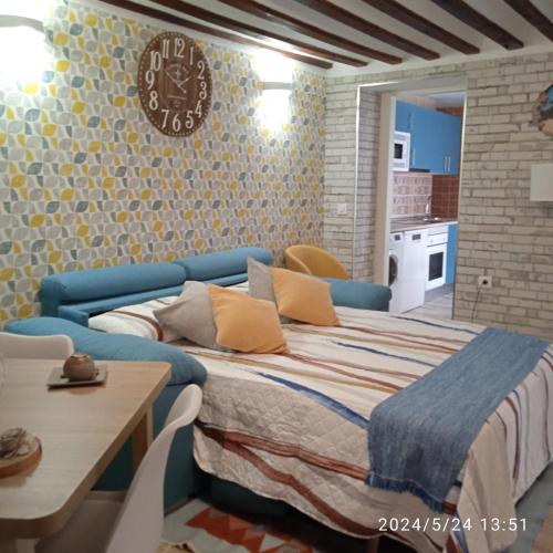 a bedroom with a bed and a table and a clock at Apartamento Turístico El Empedrado de M&G in Colmenar de Oreja