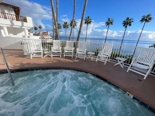 a hot tub on a patio with chairs and the ocean at Oceanfront Villa With Breathtaking Views in Avalon