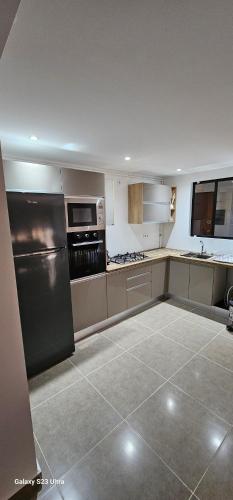 a large kitchen with stainless steel appliances and tile floors at Appartement Moderne et Lumineux in Ouled Moussa