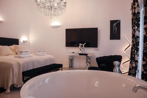 a bathroom with a tub and a bed and a tv at The White Knight Premium Boutique Hotel in Għajnsielem