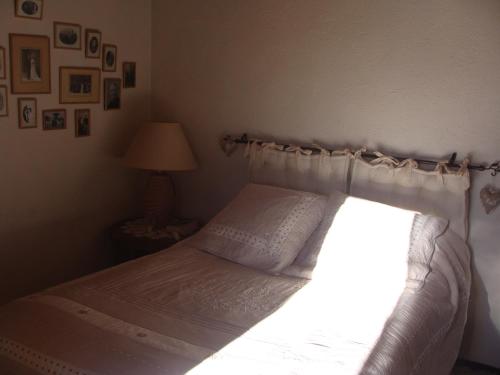 une chambre avec un lit avec des draps blancs et une lampe dans l'établissement Maison de vacances Pyrénées, à La Llagonne