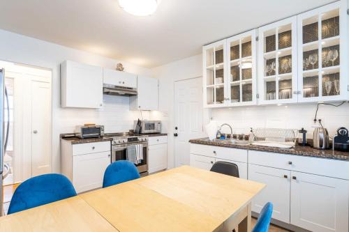 a kitchen with white cabinets and a table with blue chairs at The Blue Sapphire 2BR 2 King beds & ample backyard in Bridgeport