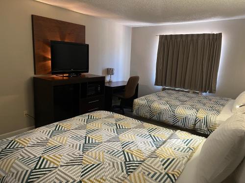 a hotel room with two beds and a flat screen tv at Motel 6 Tulsa, OK Airport in Tulsa