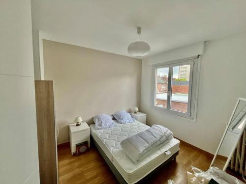 une chambre blanche avec un lit et une fenêtre dans l'établissement Le boréal, à Amiens