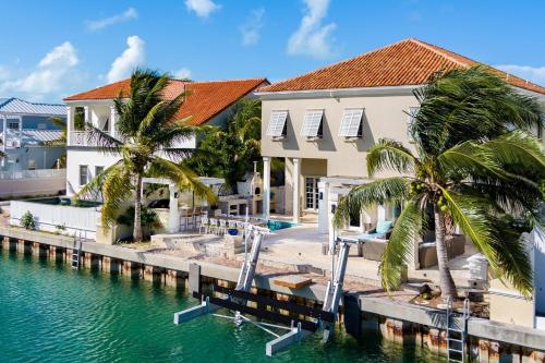 a villa with a dock and palm trees at Abundance and Prosperity Villa in Long Bay Hills