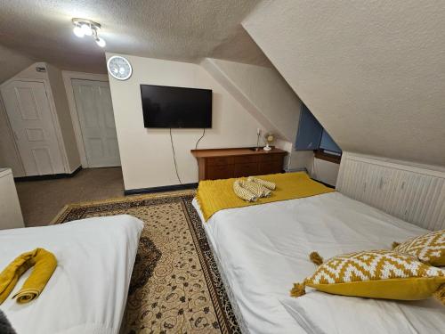 a attic bedroom with two beds and a flat screen tv at 89 Clerk Street in Loanhead