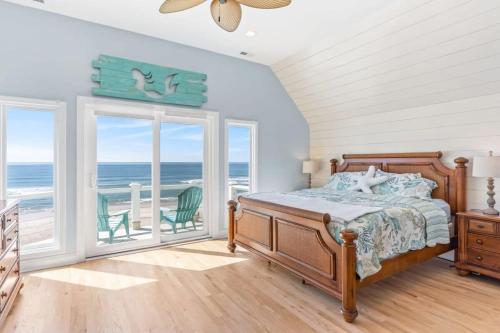 a bedroom with a bed and a balcony with the ocean at Topsail Treasure's - Oceanfront Luxury Spa Pool in North Topsail Beach
