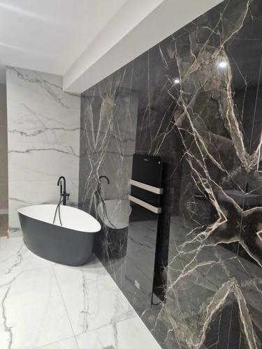 La salle de bains est pourvue d'un mur en marbre noir et blanc. dans l'établissement Maison plain-pied pour 8 personnes, à Widensolen