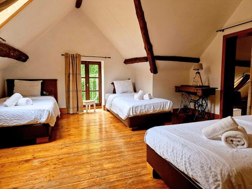 1 dormitorio con 2 camas y suelo de madera en B&B La Source de la Géronstère en Spa