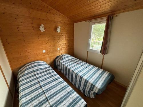 deux lits dans une petite pièce avec une fenêtre dans l'établissement Chalet climatisé 2 chambres piscine chauffée, à Agde