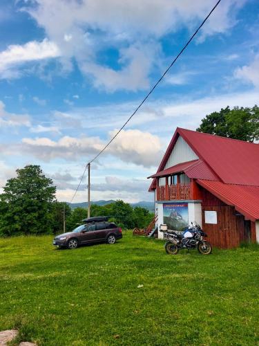 a car parked next to a barn with a motorcycle next to it at Domaćinstvo Krstajić - Rural holiday in Žabljak