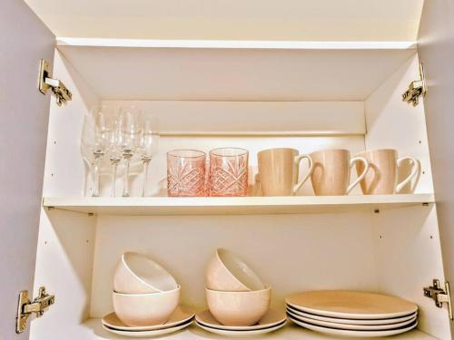 a shelf with dishes and cups and plates on it at City Zen - Patio & Pool in Auckland