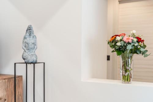 a statue of a cat sitting on a table next to a vase of flowers at Luxury 2BR w/ River Castle View in Borgo Valsugana in Borgo