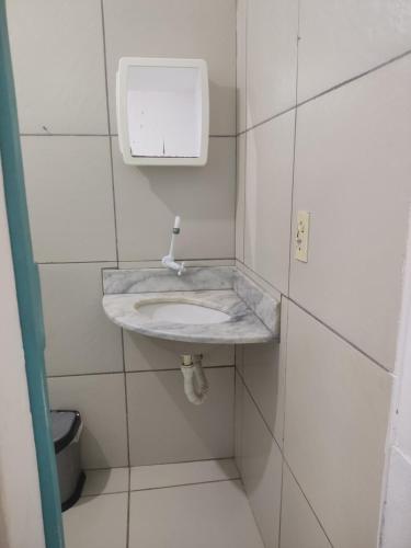 a bathroom with a sink in a white tiled wall at Hospedagens Icapui Mare Blu in Icapuí