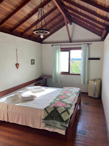 une chambre avec un lit et une grande fenêtre dans l'établissement Hotel Fazenda Capao do Indio, à Vacaria