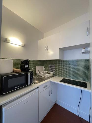 une cuisine avec des armoires blanches et un micro-ondes dans l'établissement Studio cosy avec vue sur Paris, à Paris