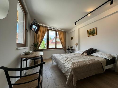 a bedroom with a bed and a table and windows at M apartments in Sarajevo