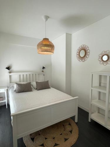 a white bedroom with a bed and a chandelier at Appart Grande terrasse in Saint-Jean-de-Luz