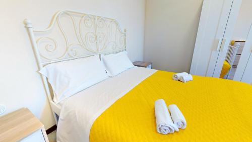 a bedroom with a yellow and white bed with two towels at Casal Trinacria in Santa Teresa di Riva