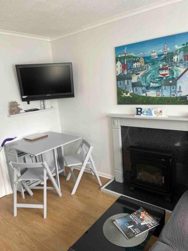 a living room with a table and a fireplace at Bermuda Sands Hemsby Chalet in Hemsby