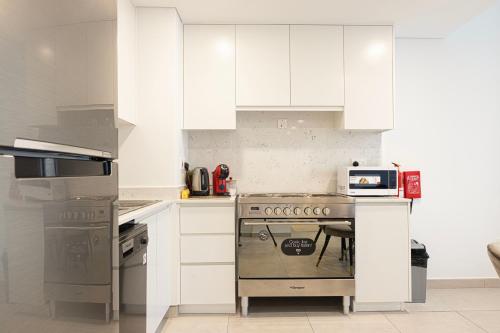 a kitchen with white cabinets and a stove at Spectacular 2BR Apartment Full BurjAlArab View in Dubai