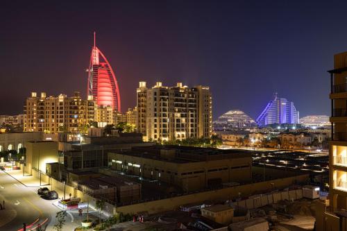 a city skyline at night with a red building at Spectacular 2BR Apartment Full BurjAlArab View in Dubai