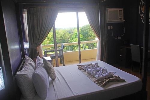 a bedroom with a bed with a view of a balcony at Hotel Palacio Puerto Princesa in Puerto Princesa City