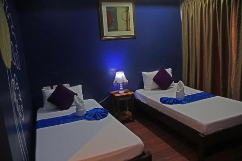 two beds in a room with a blue wall at Hotel Palacio Puerto Princesa in Puerto Princesa City