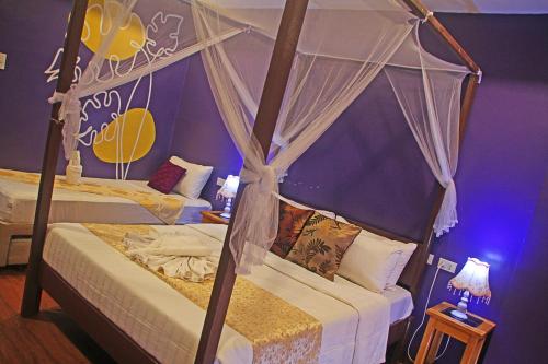 a bedroom with two beds with a canopy at Hotel Palacio Puerto Princesa in Puerto Princesa City