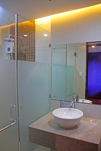 a bathroom with a sink and a glass shower at Hotel Palacio Puerto Princesa in Puerto Princesa City