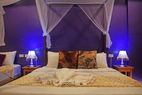 a bedroom with a bed with a canopy and two lamps at Hotel Palacio Puerto Princesa in Puerto Princesa City