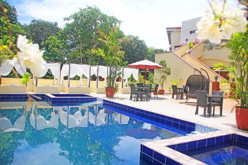 a swimming pool with tables and chairs next to a building at Hotel Palacio Puerto Princesa in Puerto Princesa City