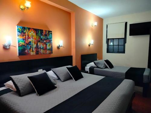 a room with two beds and a painting on the wall at Hotel La Herreria Colonial in Popayan