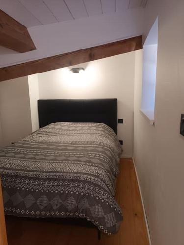 Ce lit se trouve dans une petite chambre dotée de parquet. dans l'établissement Chez David - Vacances sous les toits, à Brioude