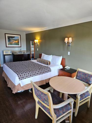 a hotel room with a bed and two tables and chairs at Fullerton Inn in Fullerton